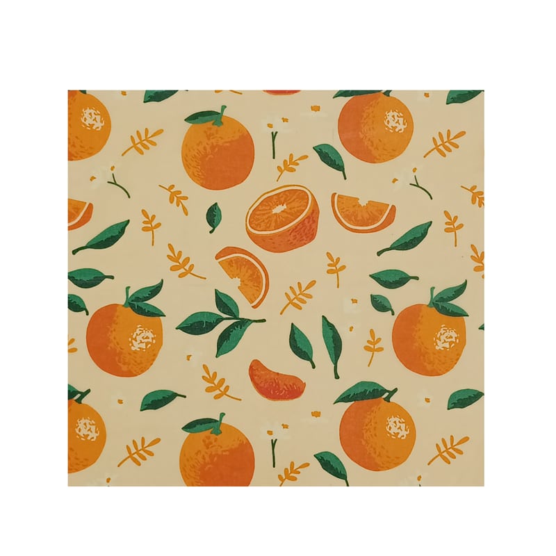 Colorful beeswax food wrap pattern featuring whole oranges, orange slices, and green leaves on a light beige background. The design is repeating and includes various orange shapes and sizes, along with stylized leaf elements.