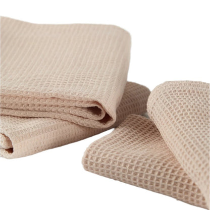 Close-up of light pink waffle-textured kitchen towels, showing folded and draped arrangements to highlight the fabric&