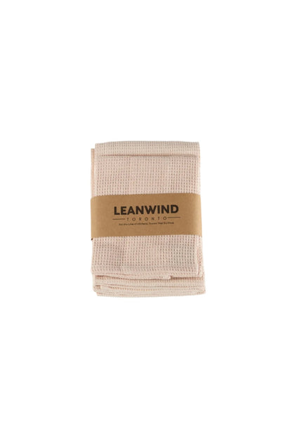 Folded light pink waffle-textured kitchen towels with a brown paper band labeled &quot;LEANWIND TORONTO&quot; wrapped around the middle, displayed on a white background.